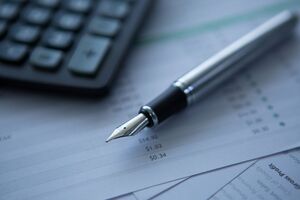 Silver fountain pen resting on financial statements showing net revenue and gross profit metrics for hotel GDS distribution strategy.