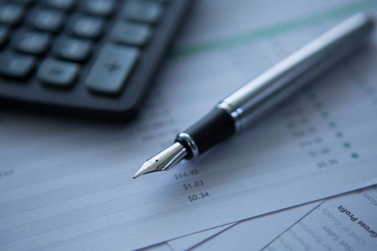 Silver fountain pen resting on financial statements showing net revenue and gross profit metrics for hotel GDS distribution strategy.